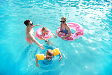 Happy family swimming in pool on summer day