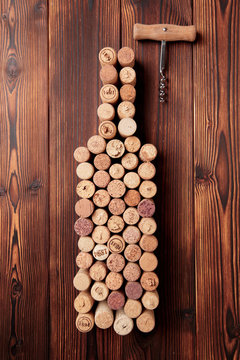 Wine bottle shaped corks and corkscrew over rustic wooden table background and burlap. Top view with copy space - image