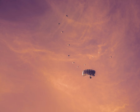 Silhouette of Paragliders flying in formation on sunset background