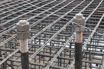 Two steel anchor bolts with screw nuts and steel grid on tower crane footing reinforcement © Philipp Berezhnoy