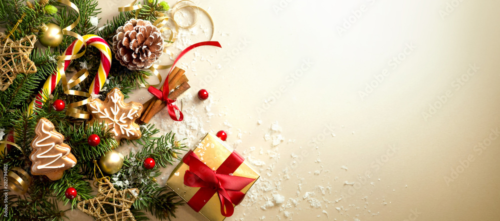 Wall mural christmas decoration composition on light gold background with beautiful golden gift box with red ri