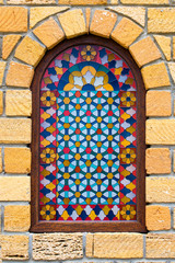 Stained glass window in the yellow stone wall