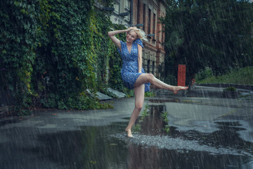 Young woman frolics barefoot through puddles in the summer rain.