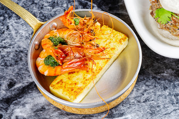 Close up view on traditional grilled polenta with large shrimp. Italian appetizers. Fried corn sticks. Seafood for lunch. Mediterranean cuisine. Flat lay food on marble table
