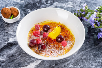 Close up view on bowl with Creme brulee (cream brulee, burnt cream) and berry, truffle. Restaurant food style. French vanilla cream dessert with caramelised sugar on top