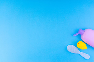 Fototapeta na wymiar Flat lay composition of baby care products on a blue background. View from above shampoo or shower bottle gel, cleaning brush and yellow rubber toy duck
