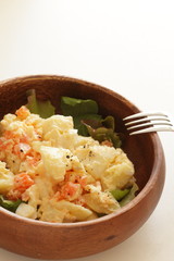Potato and carrot salad on wooden bowl