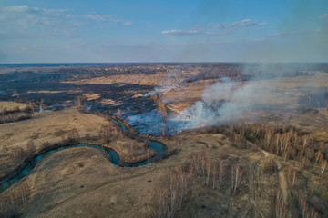 Forest fire. Dry grass burning in the field, near the river.
