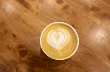 Paper cup of cafe latte on wooden table background