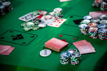 A poker table with casino chips and cards on greencloth, background with selective focus