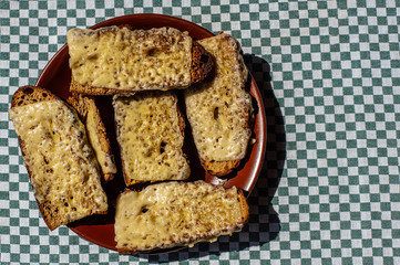 Crispy hot toast with cheese on a brown clay plate