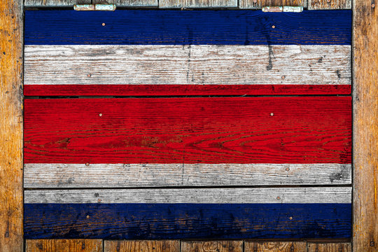 National flag of Costa Rica on a wooden wall background.The concept of national pride and symbol of the country.Flag painted on a wooden fence with metal nails.
