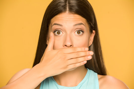 Young surprised woman covers her mouth with her hand