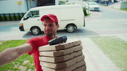 Happy pizza corrier visiting house with boxes to the customer. Convenient fast food home delivery services. Portrait of cheerful young deliveryman holding boxes with hot pizza standing by door.