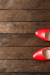 Red high heels on wooden background with copyspace. Top view