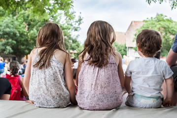 Trois enfants sages de dos regardant un spectacle attentivement