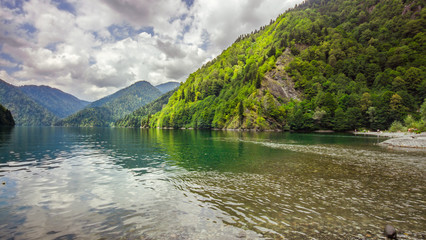 Natural landscape. Panorama view of the lake Small Ritsa. Trees reflecting in the blue from lapis...