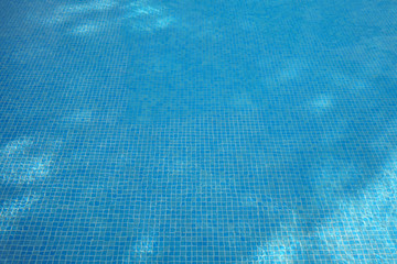 Blue sunlit water in a swimming pool.