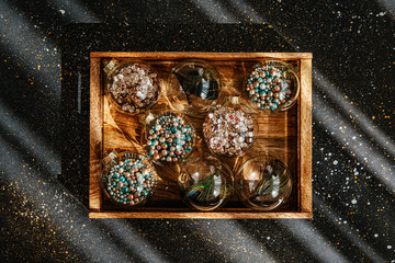 Christmas glass transparent ball with colorful sparkle confetti and decoration in wooden box. Christmas concept
