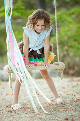 Little girl riding on a swing. 