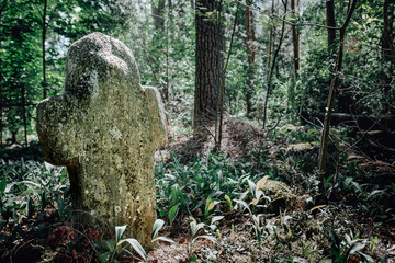 stone cross in the summer forest at the cemetery
