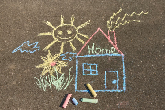 Children's drawing with chalk on the asphalt: a house with the inscription home , sun and flower.