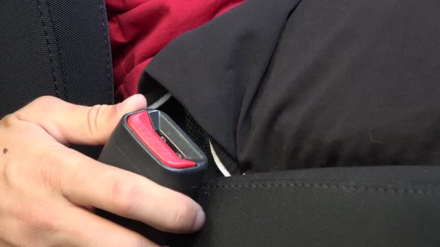 4k.UHD. Caucasian man fastening seat belt on car. Passengers sitting inside the car wearing a safety belt while waiting for the start. Safe travel is importance while traveling on car flight trip.