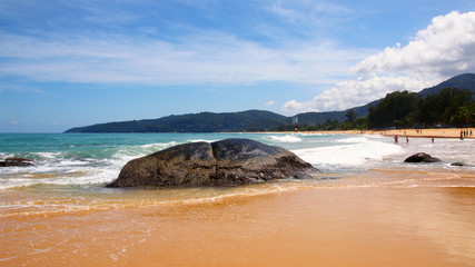 Boulders, the surf, and the blue sky over the sea, Karon sandy beach, Thailand