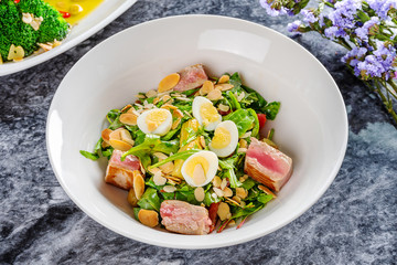 Close up view on tasty salad with grilled tuna, microgreen, small egg on marble table. Mediterranean and italian cuisine. Italian appetizer. Flat lay. Seafood. Helathy meal