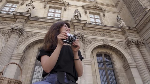 Beautiful young woman with dark hair, wearing jeans and black t-shirt is taking pictures of the city. Real time portrait shot