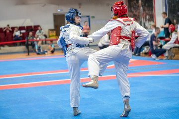 Fototapeta premium two girls in blue and red Taekwondo equipment are fighting at doyang