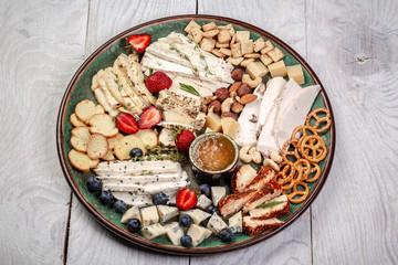 Cheese plate served with blueberry, strawberry, crackers and nuts, Top view. Assorted cheeses Camembert, Brie, Parmesan blue cheese, goat