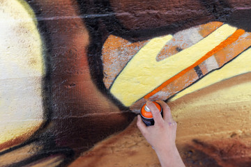 Graffiti Artist hands with paint cans against gray wall
