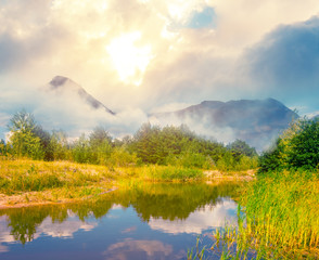 beautiful mountain valley with small lake and forest at the sunset, natural evening background
