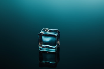 clear transparent ice cube on emerald background