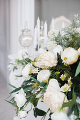 a bouquet of white roses, peonies, dahlias and eucalyptus branches and candles on the bedside table