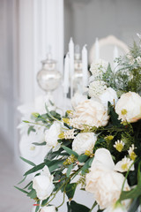 a bouquet of white roses, peonies, dahlias and eucalyptus branches and candles on the bedside table