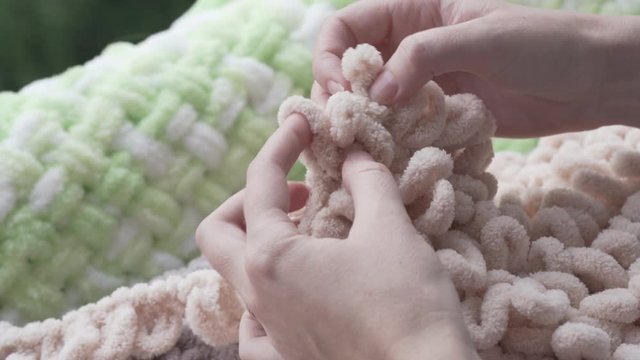 Girls is knitting with Alize puffy yarn without any hooks or needles