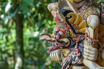 Fototapeta premium Balinese ancient colorful bird god Garuda with wings, closeup. Religious traditional statue from wood. Wooden old curved figure of Hindu god in Island Bali, Ubud, Indonesia