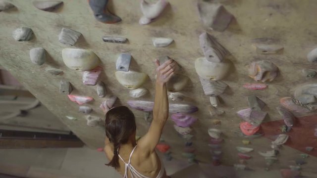 Young Woman Rock climber is Climbing At Inside climbing Gym. slim pretty Woman Exercising At Indoor Climbing Gym Wall, slow motion stock footage