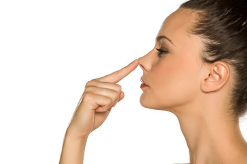 young woman touches her nose with her finger on a white background