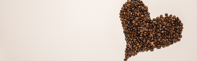 top view of heart made of coffee grains on beige background, panoramic shot