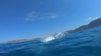 Handsome young man jumping from a boat or yacht into the sea or ocean. Summer vacation with friends. Tourists have fun and dive. Slow motion.