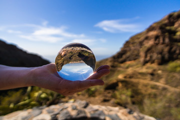 Lensball auf der Hand mit Blick zum Meer und auf Berge