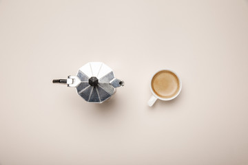 top view of metal coffee pot and coffee cup on beige background