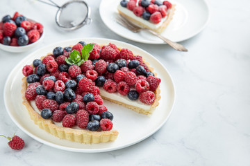 blueberry  and raspberry tart  on white marble background