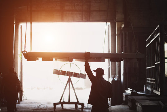 A crane lifts a stove at a factory. Worker controls the lifting process. - Powered by Adobe