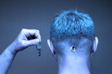 A man with a keyhole in the back of his head holds keys in a raised hand