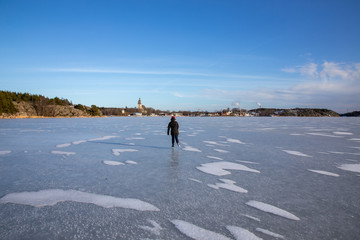 Ice skating over the frozen baltic sea in Naantali, Finland. Sunny winter day with blue sky. Girl ice skating.