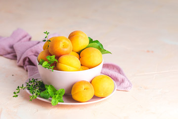 Fresh sweet orange apricots in pink bowl on the pink concrete surface table, selective focus, shallow depth of the fields